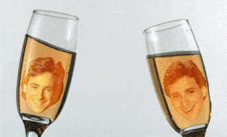 Digital art gif. Bob Saget as Danny from Full House. Danny's face is edited to be floating inside two champagne flutes and they cheers together while his face grins happily.