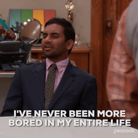 TV gif. Aziz Ansari as Tom Haverford from Parks and Rec sits at a desk in the office, shaking his head. He says what the text reads, "I've never been more bored in my entire life" 