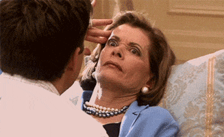 Arrested Development gif. Jessica Walter as Lucille Bluth reclines against a pillow with her fingers to her temple and a disturbed, wide-eyed, annoyed expression on her face as Michael (Jason Bateman) talks to her.