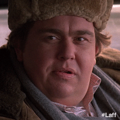 Movie gif. John Candy as Uncle Buck turns his head and gives a cheesy grin.