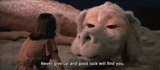Movie gif. Falkor the dragon in Neverending Story lays on its stomach and speaks to Noah Hathaway as Atreyu. Its head sways as it says, "Never give up and good luck will find you."