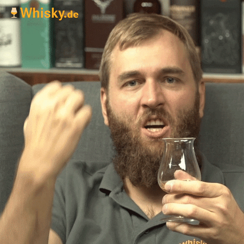 Video gif. Ben Luening from Whisky dot DE, holding a small whiskey glass, brings down his fist like he just won a bet. 