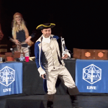 Video gif. A man in colonial era breeches, jacket, and tricorn hat strikes a lunging pose on stage and emphatically points in the air. Text, "This."