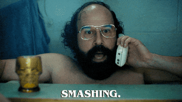 TV gif. Brett Gelman as Murray Bauman on Stranger Things lounges in his bathtub with a tray over his lap. He holds a cordless home phone up to this ear as he excitedly says, “Smashing.” 