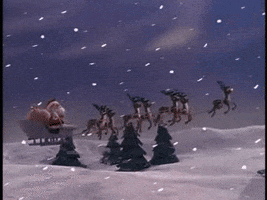 Movie gif. Scene from Rudolph The Red Nosed Reindeer as Santa. The reindeers take off in the sky and fly through a snow ridden land as snow falls around them.