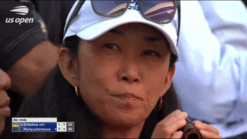 Video gif. Woman peers through a monocular from the stands at the US Open.
