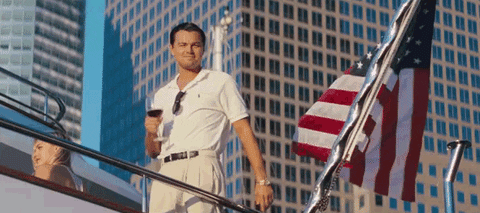 Lenodardo DiCaprio na lodi ve filmu Velký Gatsby pozvedající číši s červeným vínem.