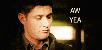 TV gif. Jensen Ackles, as Dean in Supernatural gives a sheepish grin. Text, “Aw yeah.”