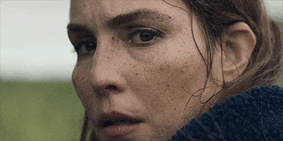 Movie gif. Noomi Rapace as Maria in Lamb stares intently with deep worry over her shoulder. 