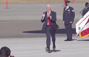Political gif. Vice President Mike Pence runs across the tarmac in a suit, clapping.