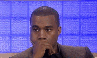 Celebrity gif. Kanye West has his hand over his mouth and he blinks mildly at nothing in particular. He looks tired or bored. 