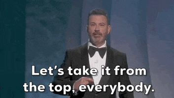 Oscars 2024 gif. Jimmy Kimmel gives a pointed hand motion to someone offstage and says, "Let's take it from the top, everybody." 