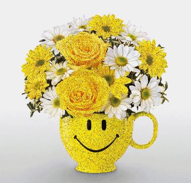 Žlutá váza ve tvaru žlutého hrníčku, zdobená usmívajícím se obličejem smajlíka, naplněná žlutými a bílými květy.