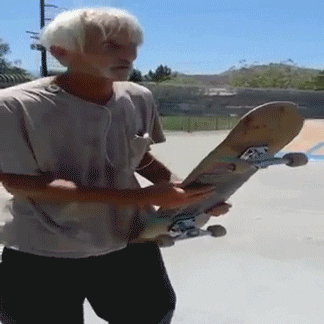 Video gif. An older man is holding a skateboard and he throws it on the pavement. He hits it midair so it bounces upright and he jumps on it, skating away smoothly.
