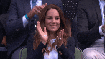 Celebrity gif. Kate Middleton sits in the stands of a game. She watches the games, smiling and clapping. People behind her clap as well.