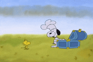 Peanuts gif. Wearing a chef’s hat, smiling Snoopy stands in front of an open chest, looking at a scowling Woodstock. Snoopy removes his hat and places it into the chest as Woodstock stomps around furiously. Snoopy rummages around in the chest and pulls out a Pilgrim hat, smiling at Woodstock as he throws the Pilgrim hat over the tiny bird. Woodstock stomps around beneath the hat angrily.
