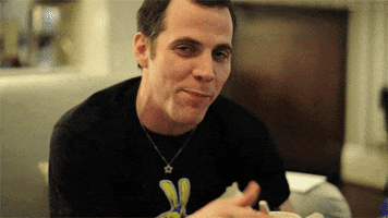 Celebrity gif. Steve-O looking healthy and happy. He gives us a thumbs up and a wink before breaking out into a smile. 