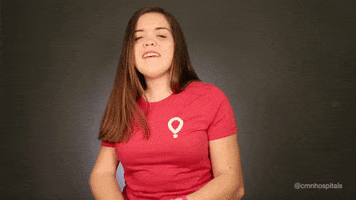 Video gif. Woman puts her hand to her chest as she smiles with surprise.