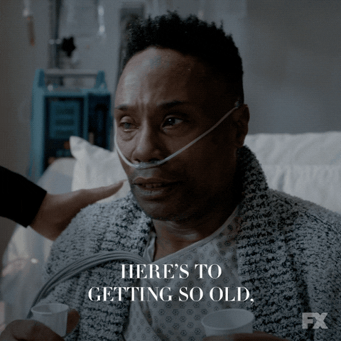 TV gif. Billy Porter as Pray in Pose sits in a hospital bed with a nasal tube on his face and says, "Here's to getting so old, folks will start calling me grandmother."