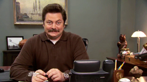 Ron Swanson (Nick Offerman) sitting in his office, giddy and happy