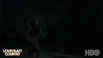 TV gif. Jurnee Smollett as Letitia Lewis in Lovecraft Country sprints through a daunting, dark forest, trying to escape what's chasing her.