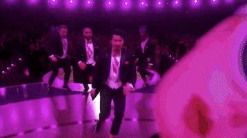 Oscars 2024 GIF. Simu Liu, leading a line of the Kens, slides into us, sexily pushing his hair back with drama.