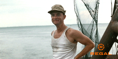 Movie gif. A grinning Tom Hanks, wearing a beige hat and a dirty, sleeveless white shirt, waves to us from the deck of a fishing boat.