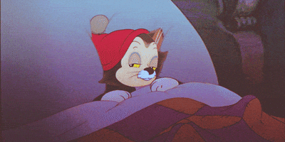Cartoon gif. Figaro the cat in Pinocchio wears a red sleeping cap and is tucked in bed. He smacks his lips and closes his eyes. He opens one eye and then turns over to his side to sleep.