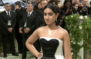 Met Gala 2024 gif. Ambika Mod wearing a white Loewe gown with a black sweetheart stain and a sleek bob, poses coldly, lost in her own mind.