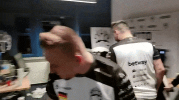 Video gif. Man sits down in a gamer chair and moves closer to the computer screen on the desk. As he scootches closer, he gives two thumbs up, shaking them around, and moving his tongue in and out of his mouth.