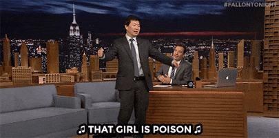Tonight Show gif. Ken Jeong dances animatedly in front of Jimmy Fallon's desk, singing as he kicks his knees up and waves his arms back and forth. Jimmy watches and laughs. Text with music notes, "That girl is poison"