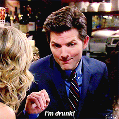 Parks and Recreation gif. Adam Scott as Ben leans forward and covers the side of his mouth as he slurs out the side of his mouth. Text, "I'm drunk!"