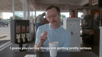 Movie gif. Aaron Ruell as Kip in Napoleon Dynamite plays with a straw in a styrofoam cup. He looks up at someone sitting across from him. Text, "I guess you can say things are getting pretty serious."