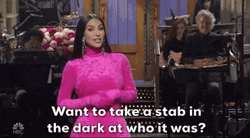 SNL gif. Kim Kardashian stands on stage wearing a fuzzy pink bodysuit as she smiles at us and asks, "Want to take a stab in the dark at who it was?"