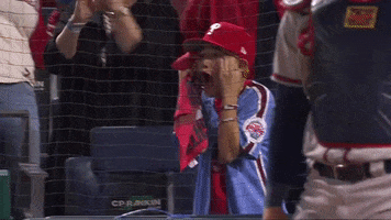 Sports gif. Phillies" player Nick Castellanos" son Liam stands up in the stands, screaming into a towel and holding his hands to his temples like he's totally amazed and it's blowing his mind. 