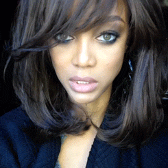 Celebrity gif. Tyra Banks stares at us intensely but also blankly, chewing gum.