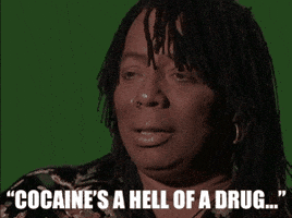 Celebrity gif. Rick James on The Chappelle Show has a very straight face as he says, “Cocaine's a hell of a drug,” and then chuckles, slightly smirking.