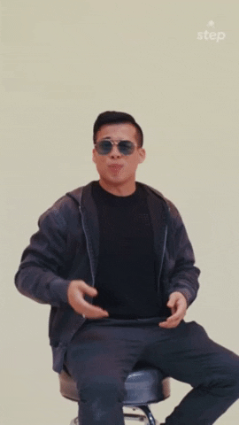 Video gif. A man sits on a stool with sunglasses on and lifts one palm up, then the other, showing the two options. Text, "This or that?" 