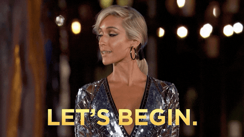 Gif of a woman in a sparkly sequin outfit smiling and saying "let's begin"