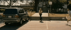 Video gif. A man walks toward a woman bringing groceries to her car and throws a pile of papers in her face, then dances. Text, “Facts.”
