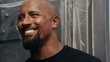 Movie gif. Dwayne Johnson as Hobbs in Fast 5 turns to reveal news with a charming but wicked grin. 
