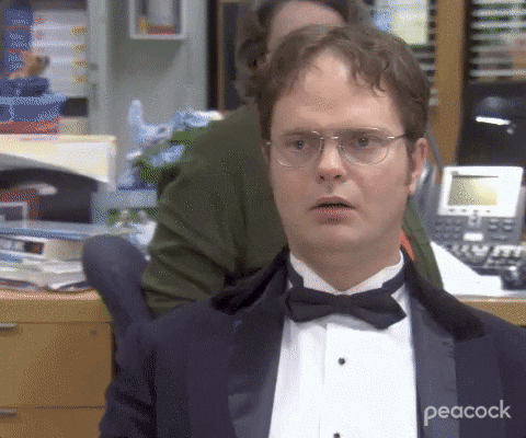 The Office gif. We zoom in on a stunned Rainn Wilson as Dwight in a tuxedo. Dwight's blank expression does not change as he speaks. Text, "Oh my god."