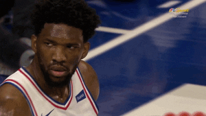 Sports gif. Basketball player Joel Embiid shakes his head during a game, wagging his finger.