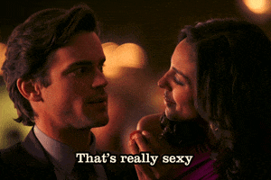 Celebrity gif. Donning a suit and tie, Matt Bomer raises his eyebrows at a woman feeding him a strawberry and says, "That's really sexy."