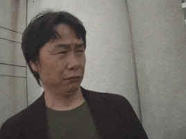 Video gif. Nintendo game director Shigeru Miyamoto leans back while judgmentally squinting his eyes and furrowing his eyebrows at something.