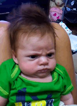 Video gif. Footage of an angry-looking baby with his hair sticking up. A finger pokes him in the side, and while his eyes widen slightly, he shows no real change in expression.