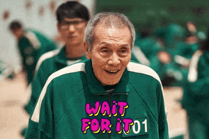 Photo gif. O Yeong-su as Oh Il-nam in Squid Game. He is smiling in anticipation of the game's start and the text reads, "Wait for it."