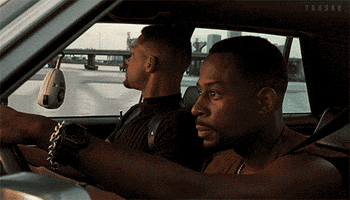 Movie gif. From the movie Bad Boys, Martin Lawrence as Marcus, driving the car with Will Smith as Mike, singing along to something.  