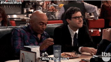 TV gif. James Lesure as Gibbs and Adam Busch as Neal Bradford sit in a restaurant booth together. Gibbs picks at his plate of food while Neal looks over at the person across from him with a concerned look on his face and says, “Who’s that now?