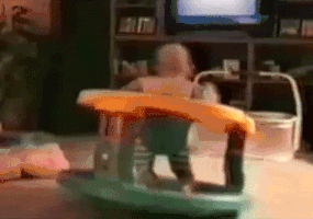Video gif. A baby in a standing toy spins in circles endlessly in a perfect loop. 